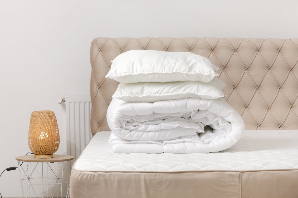 Soft folded duvet and pillows stacked at the head of a bed