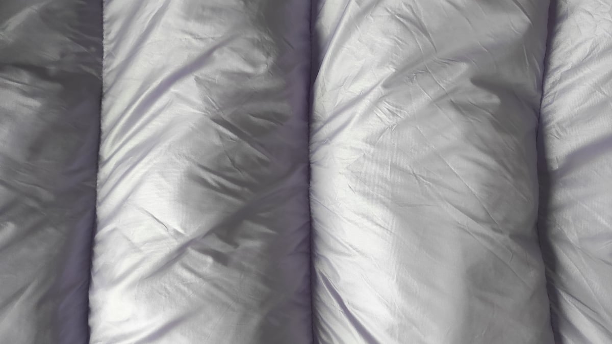 Light grey bedding arranged smoothly across a made bed