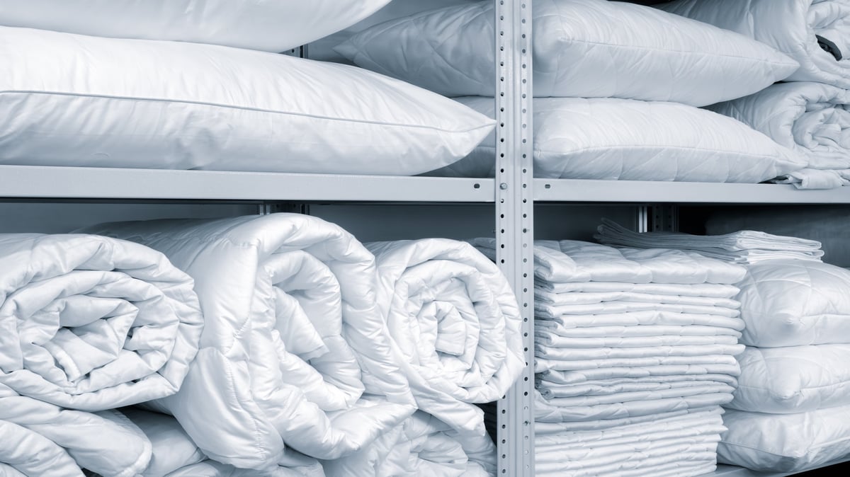 Shelves of neatly stacked white pillows and folded blankets
